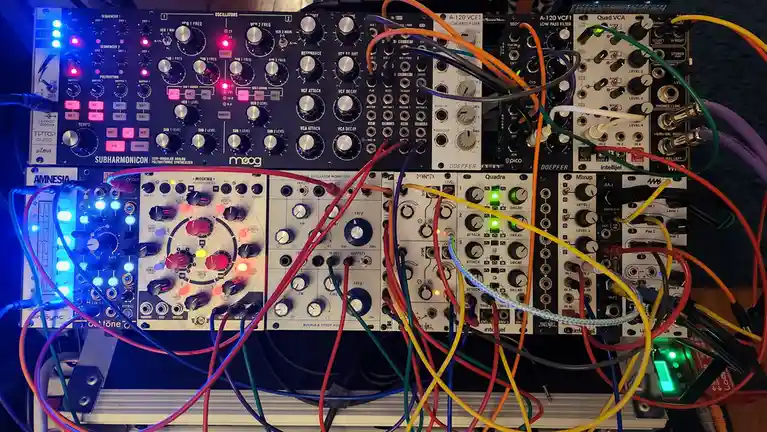 A densely packed modular synthesizer setup with multiple Eurorack modules like Moog Subharmonicon, Moskwa, and Intellijel…