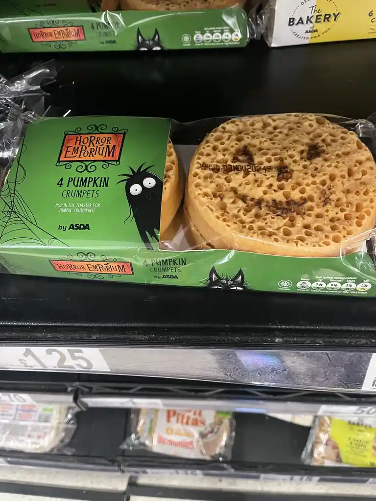 A package of Asda's 'Horror Emporium' 4 Pumpkin Crumpets sits on a supermarket shelf, its green Halloween-themed packaging…