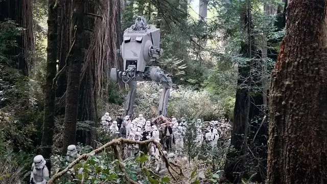 A scene from Star Wars shows a large AT-ST walker and a group of stormtroopers in a dense forest, with text overlaid that…