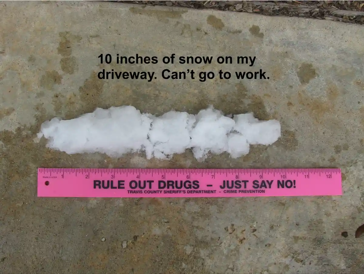 A small, compacted pile of snow sits on a concrete surface next to a pink ruler marked 'RULE OUT DRUGS - JUST SAY NO! TRAVIS…