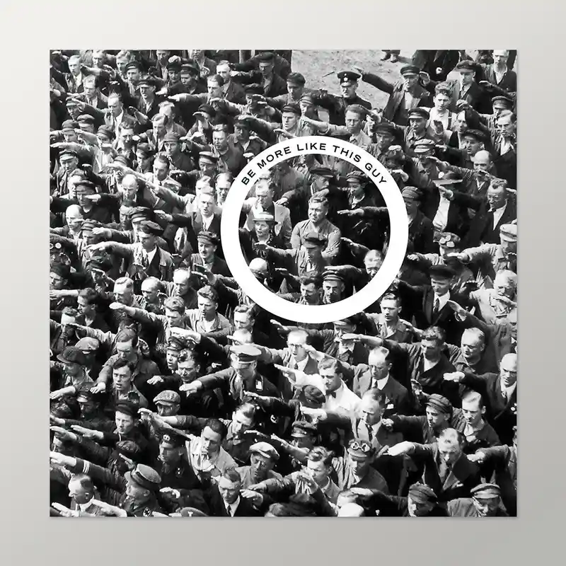 A black-and-white historical photo shows a large crowd of men in uniforms and civilian clothes, most performing a Nazi…