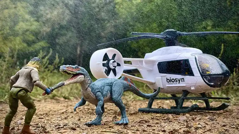 A toy action figure in a brown jacket and green pants is holding a toy weapon and facing a blue toy dinosaur with an open…