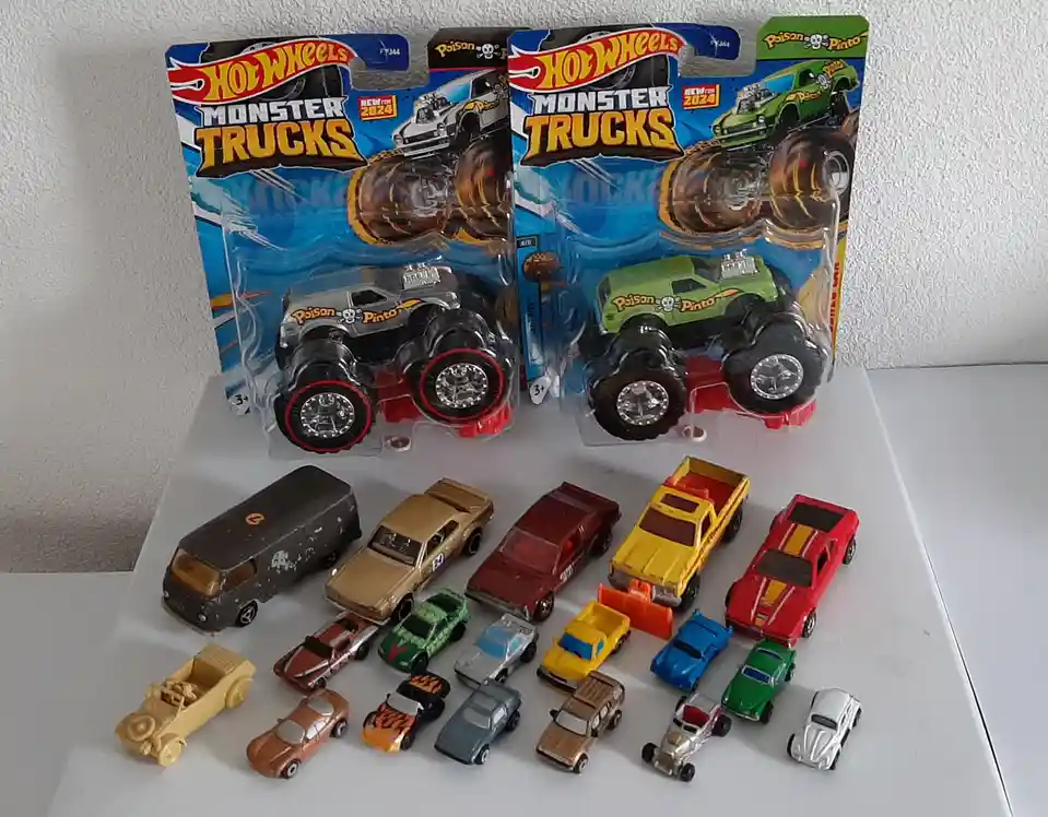 Two new Hot Wheels Monster Trucks in their original packaging, featuring 'Poison Pinto' in silver and green, sit behind a…
