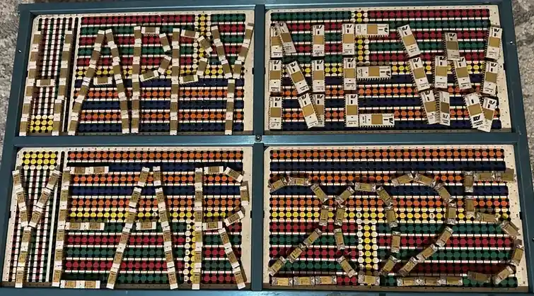 Four panels of a vintage mechanical display board, each showing a letter or number made from rows of colorful circular…