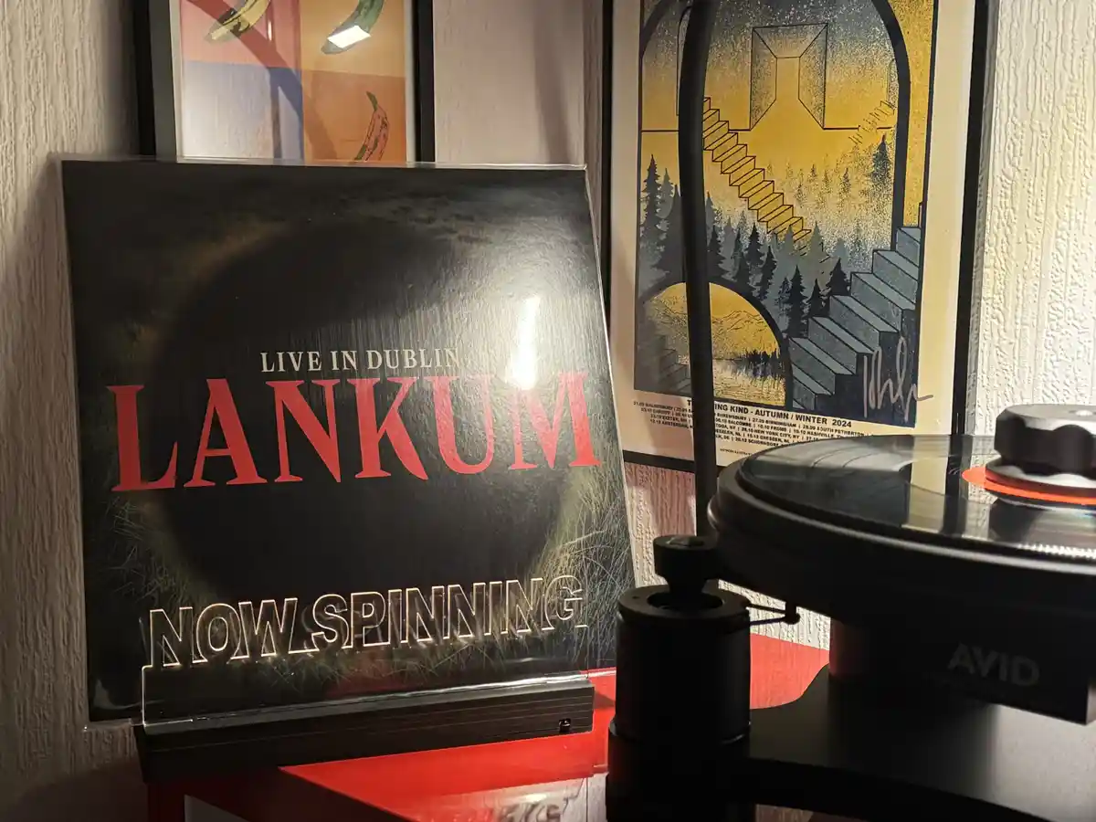 A vinyl record album titled 'Live in Dublin' by the band Lankum is displayed upright on a red surface next to a turntable…