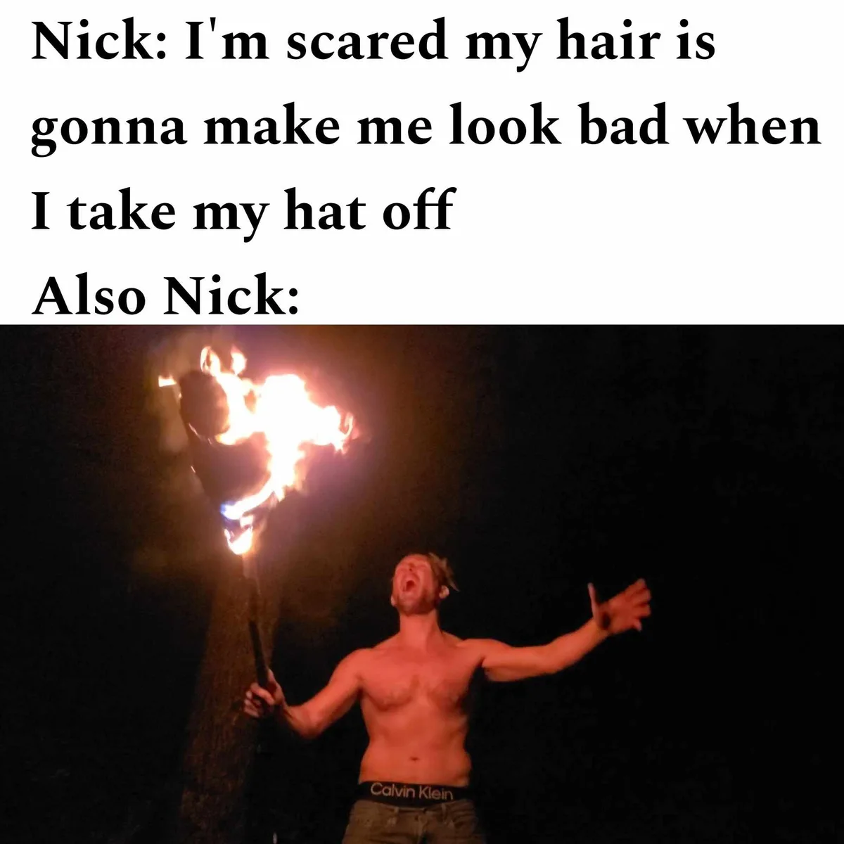 A shirtless man with a beard, wearing Calvin Klein underwear, stands at night holding a flaming torch. He has his arms…