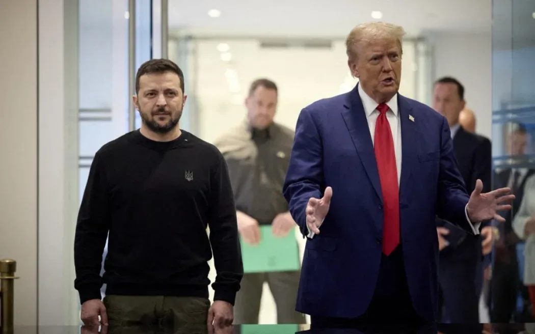 A photo shows Ukrainian President Volodymyr Zelenskyy standing still in a black sweatshirt with a small Ukrainian emblem…