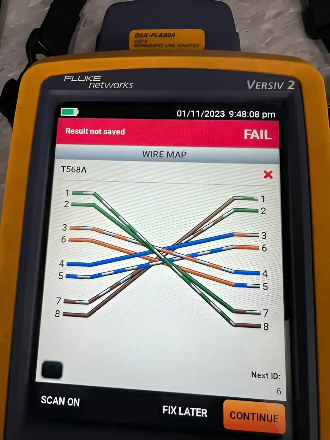 A Fluke Networks cable tester displays a 'FAIL' result on its screen, showing a wire map for T568A standard where the wires…