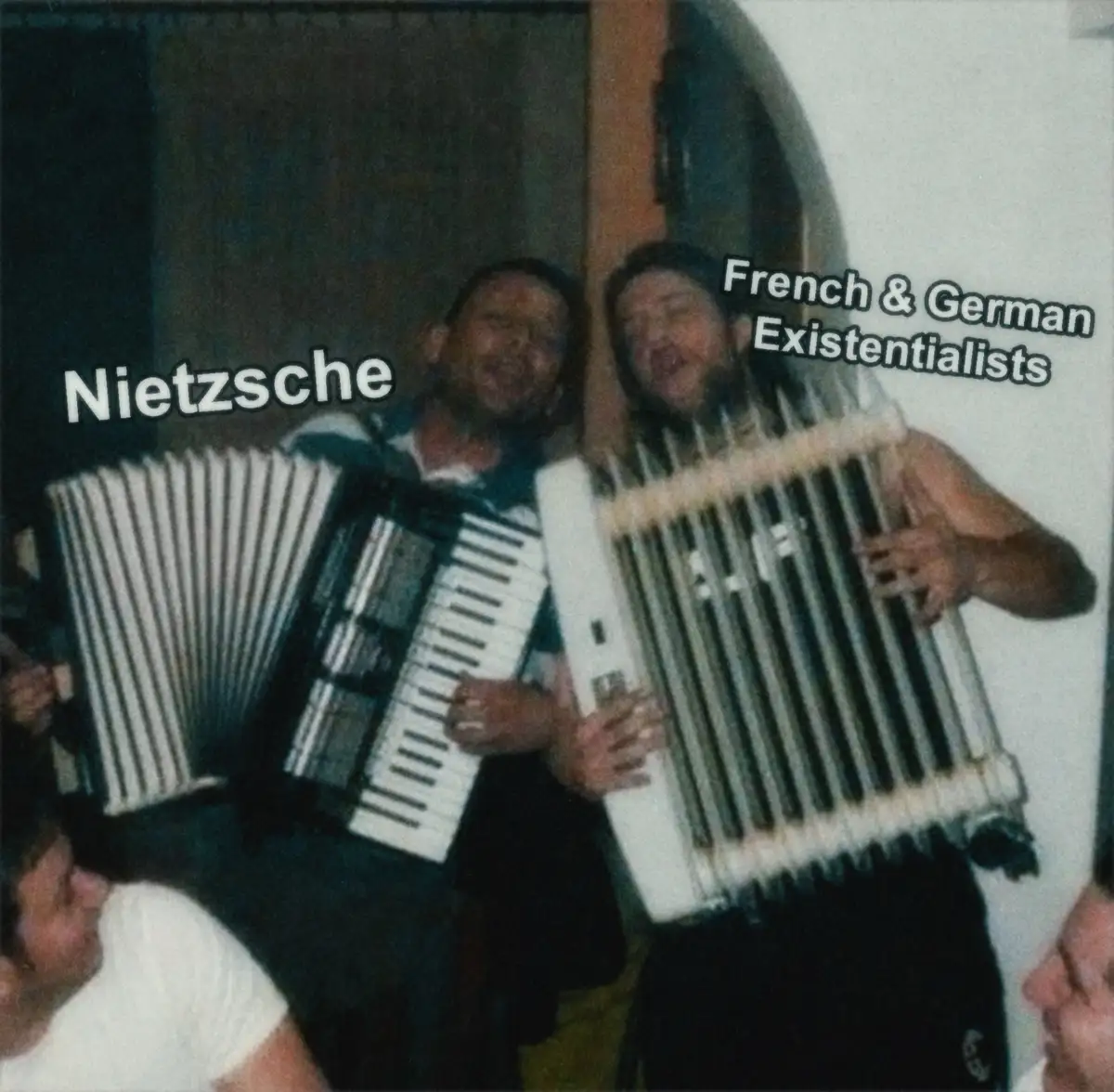 Two men are shown in a blurry, low-resolution photo, each holding a large accordion. The man on the left is labeled…