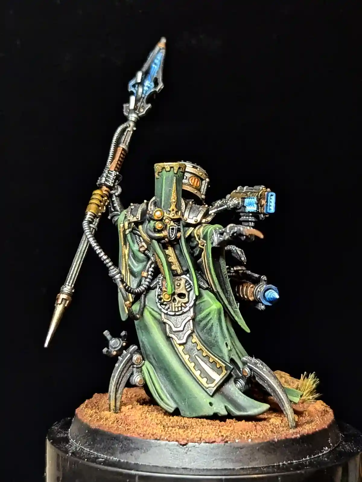 A highly detailed, painted miniature of a sci-fi warlord or necromancer in green robes and ornate armor, holding a large…