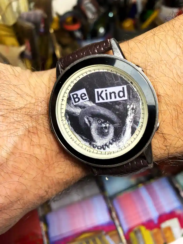 A close-up of a person's hairy wrist wearing a watch with a brown leather strap. The watch face displays a black-and-white…