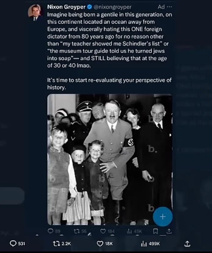 A black-and-white historical photograph shows Adolf Hitler posing with several children, some smiling, while other adults…
