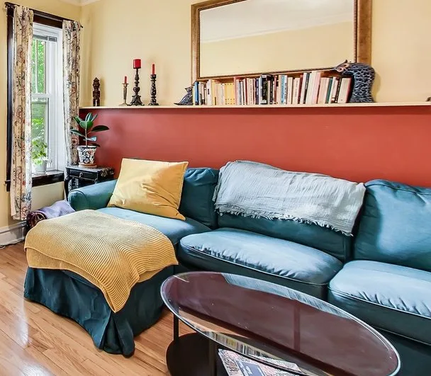 a cozy living room features a teal sectional sofa with a yellow pillow and a striped yellow throw blanket draped over an…