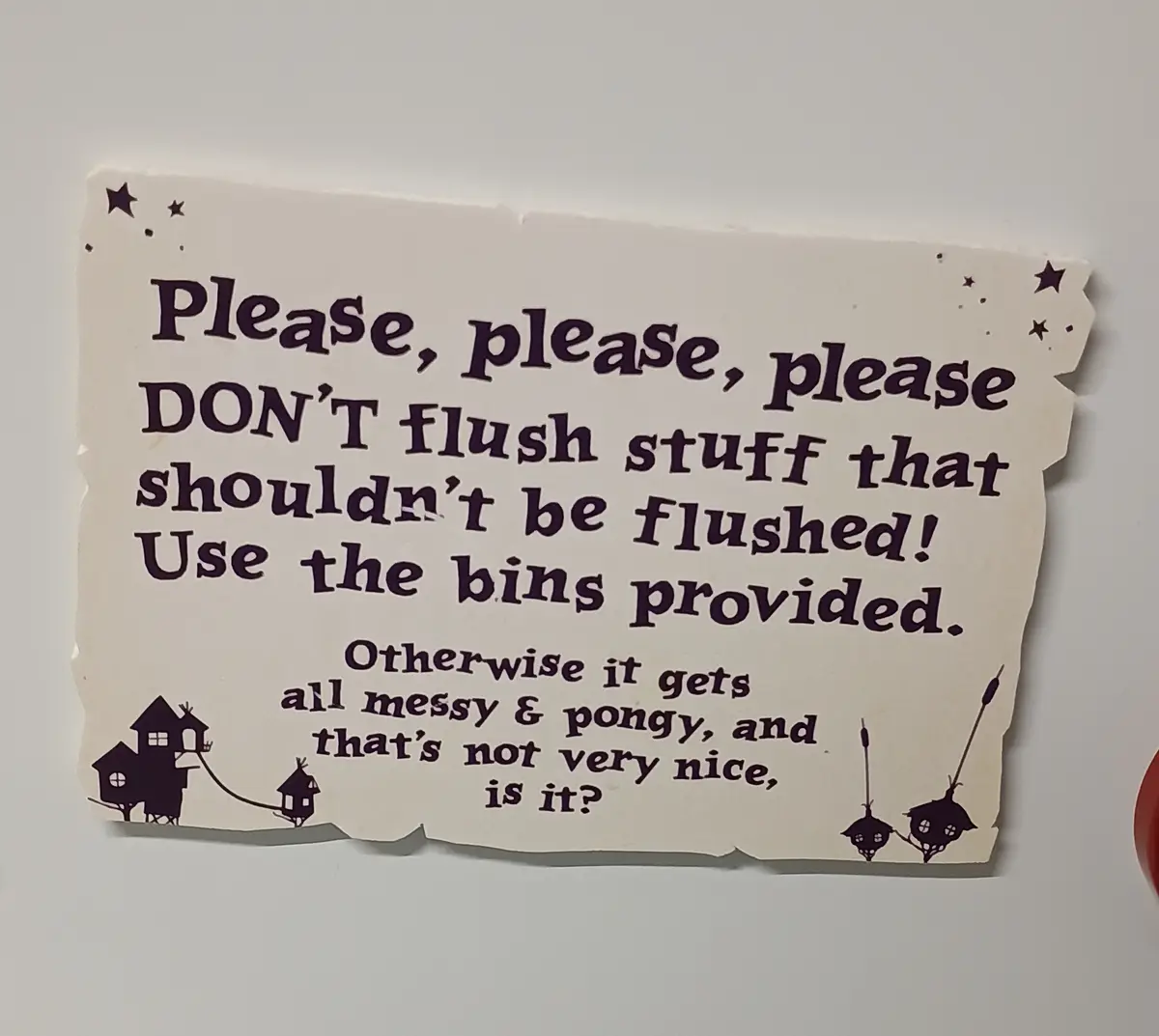 A whimsical, torn-edge sign with purple text on cream paper, mounted on a plain wall. It features cartoonish illustrations…