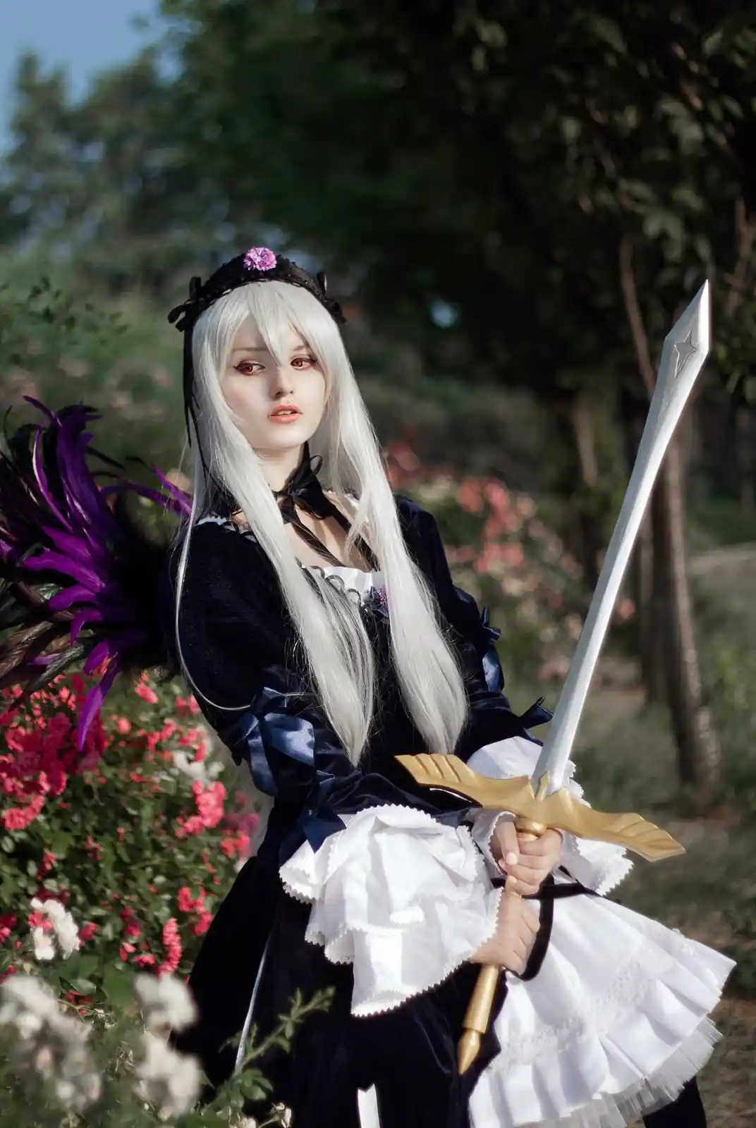 A person in a black and white maid outfit with long white hair and purple feathered wings holds a large sword outdoors among…