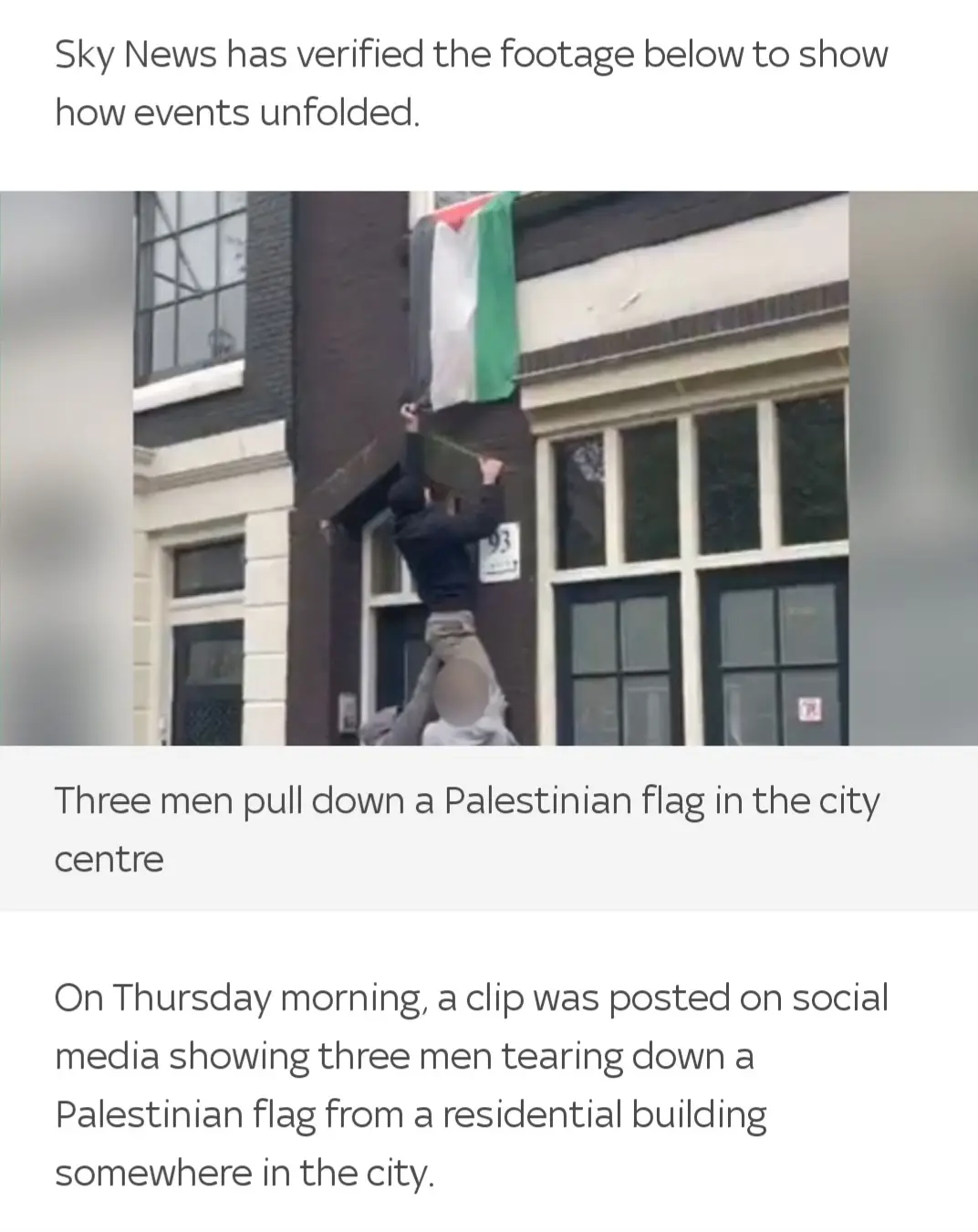 The image shows three men on a building facade, one standing on the shoulders of two others, pulling down a Palestinian…