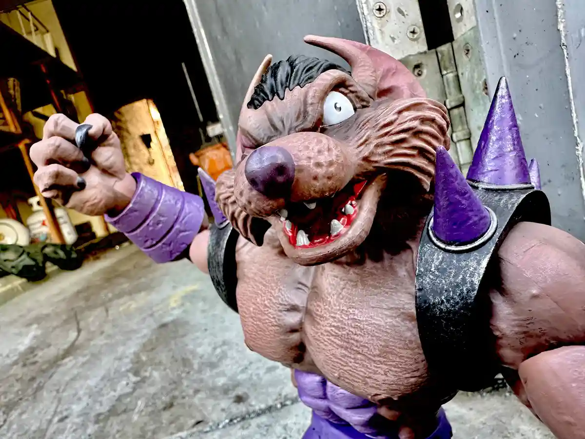 A close-up photo of a muscular, demonic-looking action figure with a pig-like snout, purple spiked armor, and a menacing…