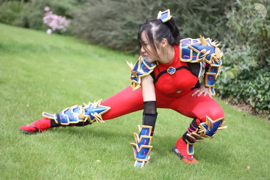 a person in a red and blue fantasy warrior costume with ornate armor pieces on their arms, legs, and head is performing a…