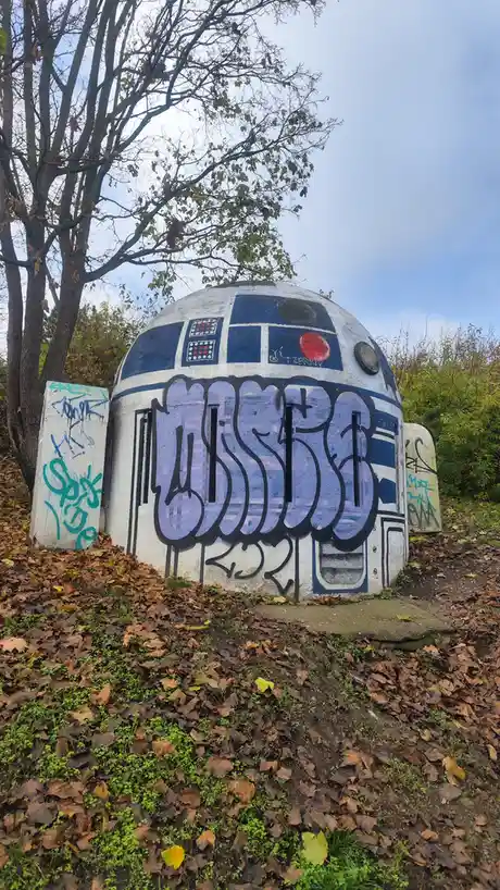 A large, dome-shaped concrete structure painted to resemble the Star Wars droid R2-D2, featuring its iconic blue and white…