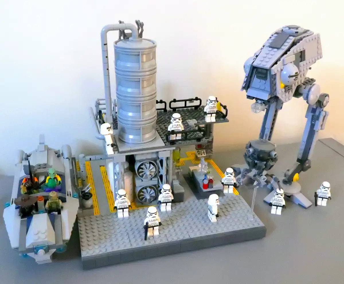 A detailed Lego Star Wars diorama featuring an AT-AT walker, a factory-like structure with pipes and fans, and multiple…