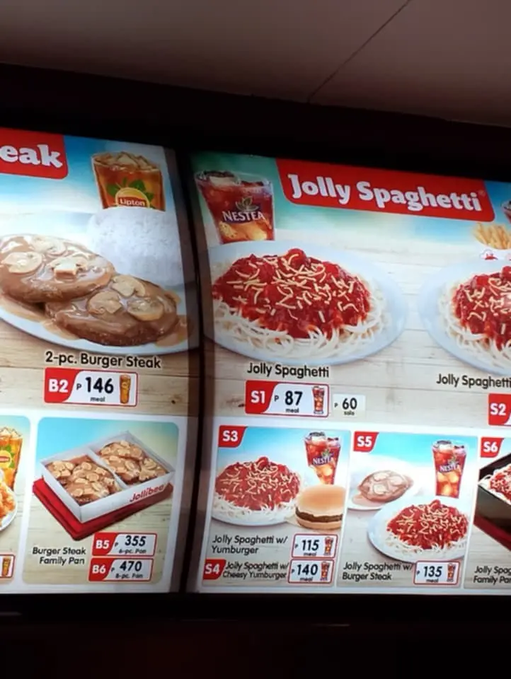 A close-up photo of a Jollibee restaurant menu board showing various food items like 2-pc. Burger Steak and multiple Jolly…