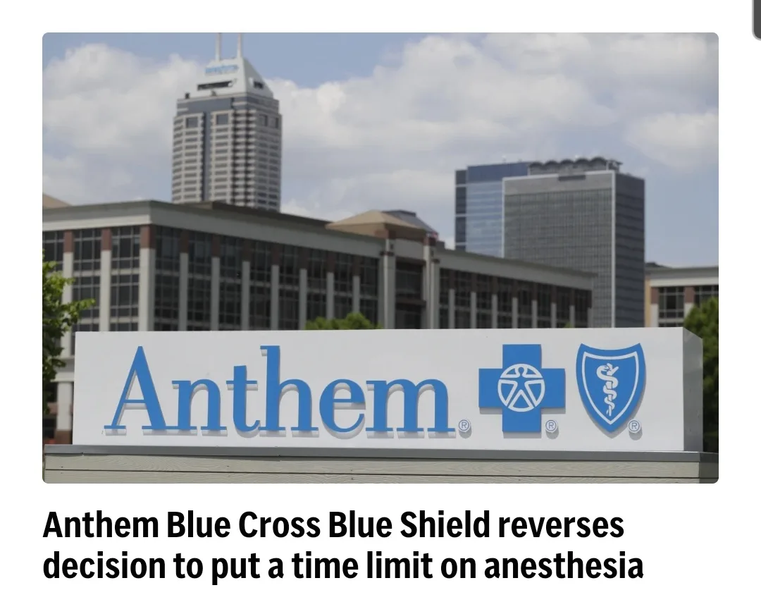 A photo of an Anthem Blue Cross Blue Shield corporate sign in front of a city skyline with skyscrapers. The sign features…