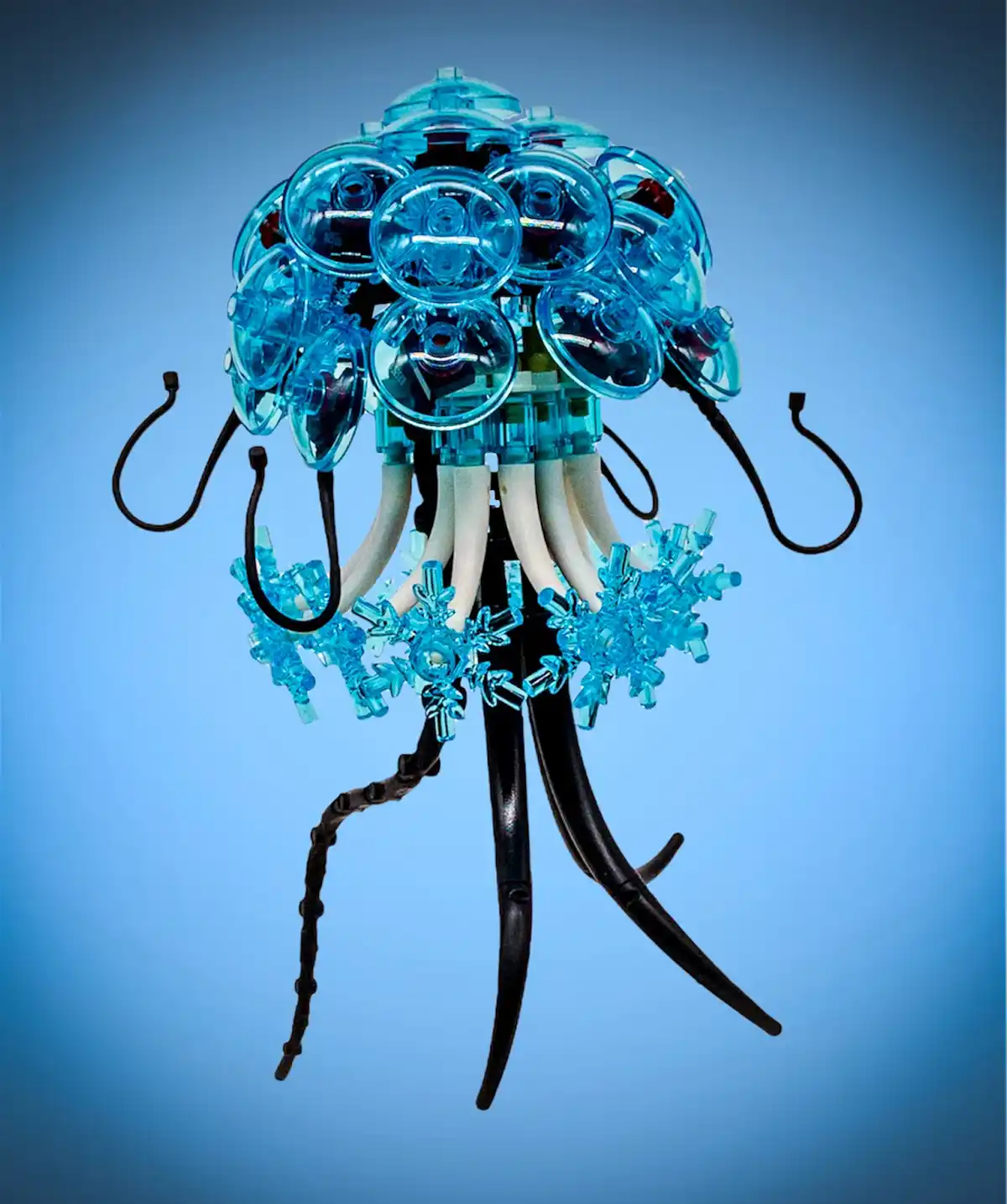 A blue translucent LEGO jellyfish model with a dome-shaped head made of circular pieces, white tentacles, black hooks, and…