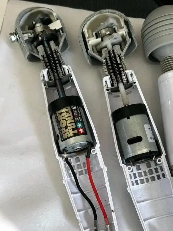 Two disassembled robotic legs lie side by side, revealing their internal motors and wiring. The left leg has a motor labeled…