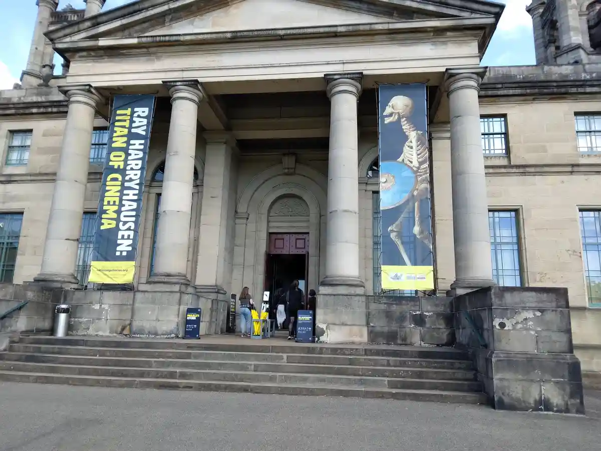 A grand neoclassical building with large columns and steps, featuring two banners. The left banner reads 'RAY HARRYHAUSEN…