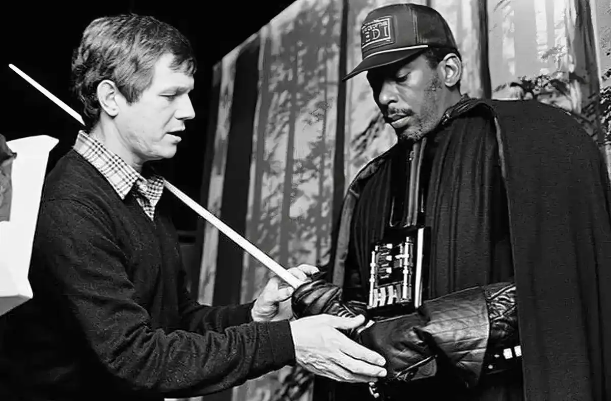 A black-and-white image shows actor Harrison Ford (as Han Solo) handing a lightsaber to actor Samuel L. Jackson (as a…