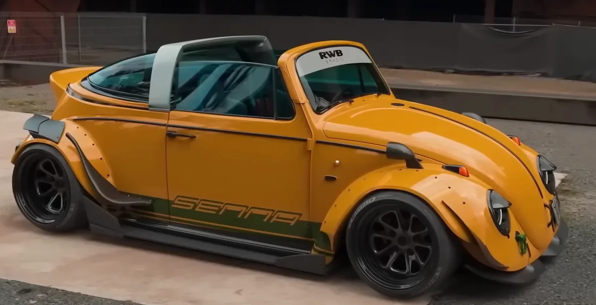 A heavily modified, bright yellow Volkswagen Beetle with widebody kit, black wheels, and 'SENNNA' written in green on the…