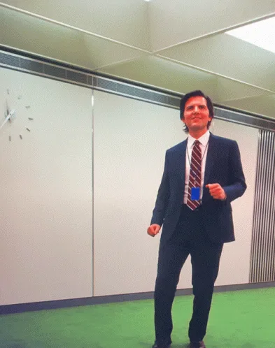 A six-panel grid shows a man in a dark suit and striped tie standing in an office with a green carpet and white walls. He…