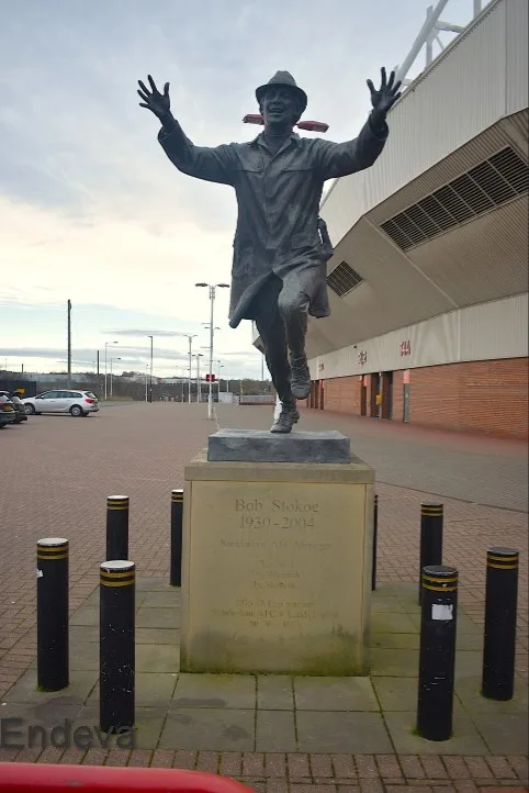 A bronze statue of Bob Stokoe, a former Sunderland AFC manager, stands with arms raised in celebration outside a stadium…