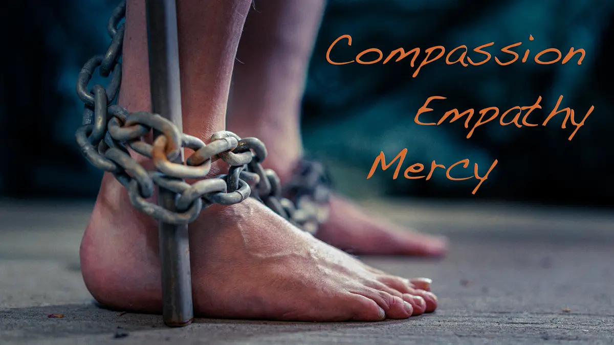 A close-up image shows a person's bare feet chained to a metal pole, with the words 'Compassion', 'Empathy', and 'Mercy'…