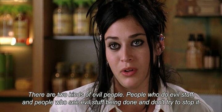 A still from the movie 'Mean Girls' shows a woman with dark eye makeup and messy hair looking intensely at the camera. She…