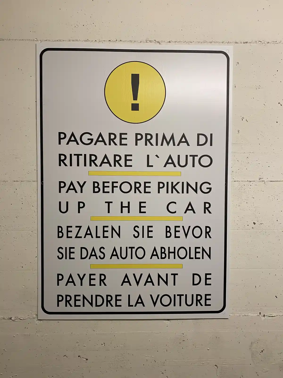 A multilingual parking sign with a yellow exclamation mark at the top, displaying instructions in Italian, English, German…