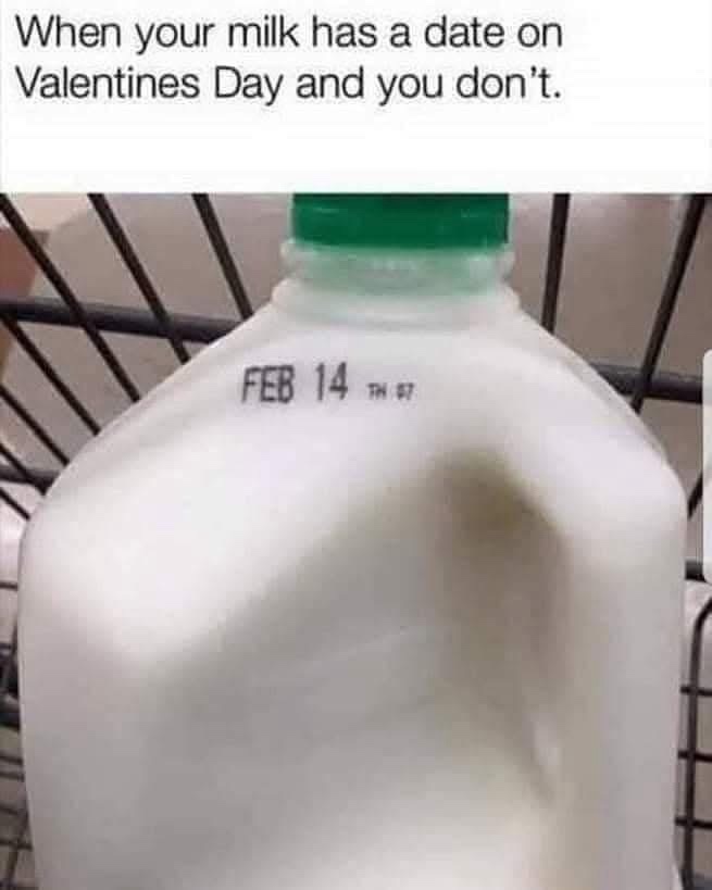 A close-up photo of a white plastic milk jug with a green cap, sitting in a metal wire shopping cart. The jug has a printed…