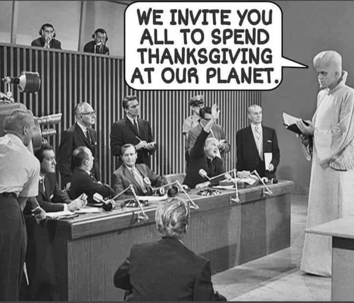 A black-and-white photo from a 1960s TV show depicts a man in a white robe standing before a panel of men in suits seated at…