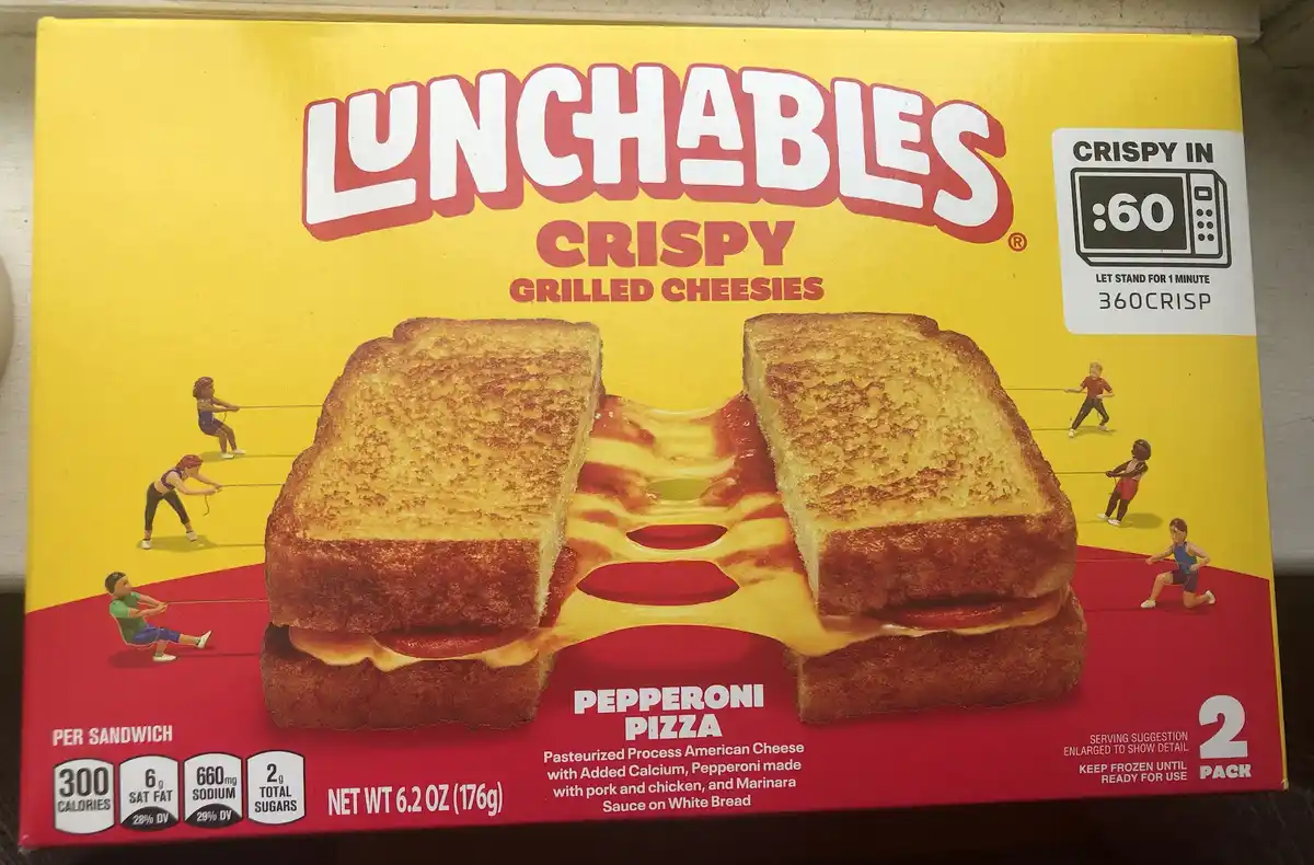 A yellow and red Lunchables box for 'Crispy Grilled Cheesies' Pepperoni Pizza shows a split grilled cheese sandwich with…