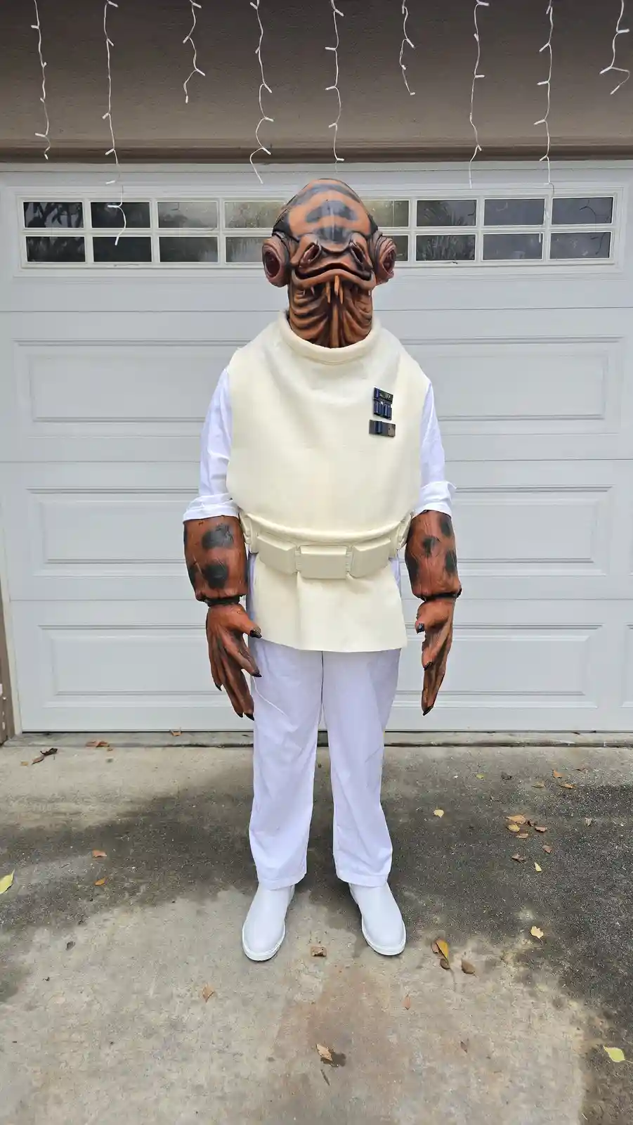 A person in a full-body costume stands in front of a white garage door. The costume is a detailed, full-body replica of a…