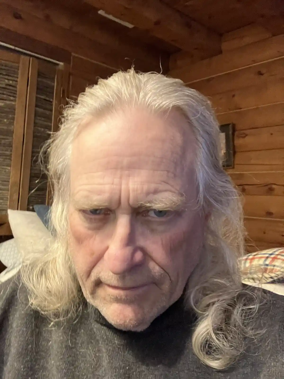 A close-up photo of an older man with long white hair and a stern, disappointed expression, looking directly at the camera…