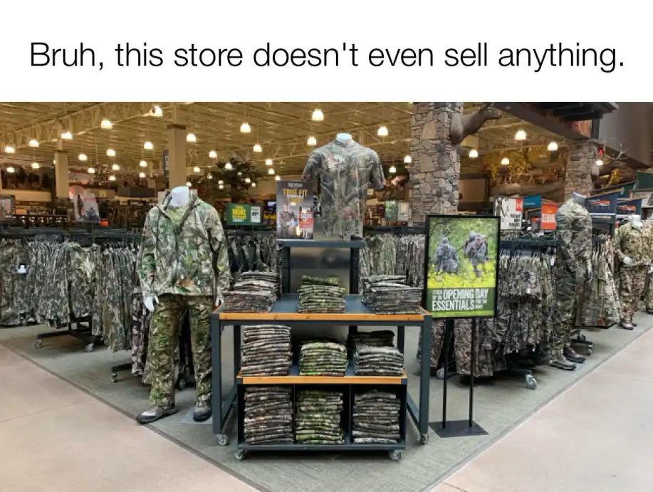 An interior shot of a retail store aisle filled with racks and mannequins dressed in camouflage clothing, with shelves…
