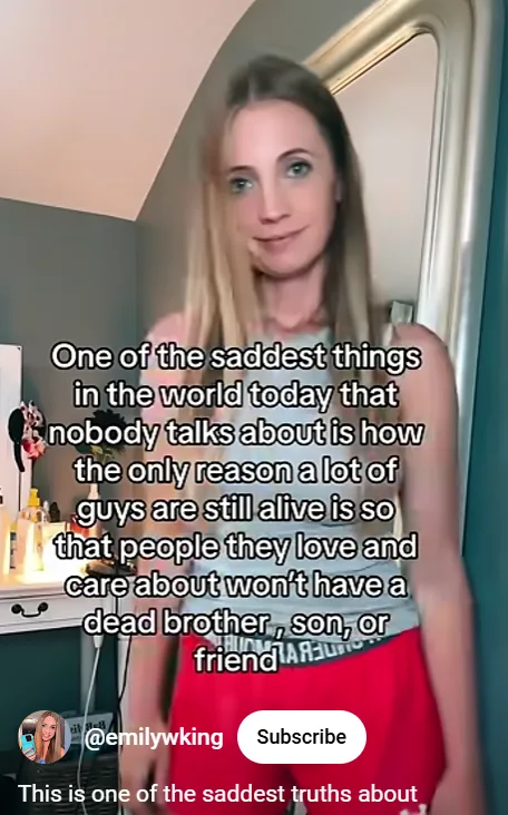 A woman with blonde hair and a slight smile stands in a room with a mirror behind her. Text overlaid on the image reads…