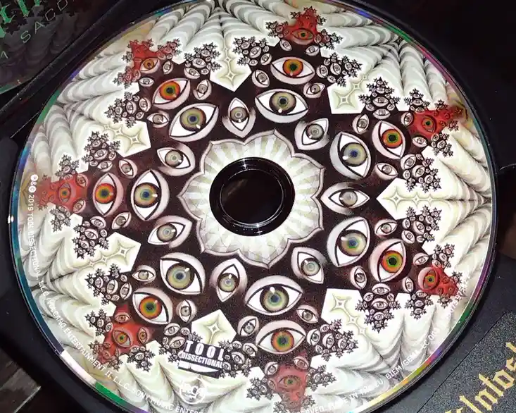 A close-up photo of a Tool band CD titled 'Dissectional' featuring a psychedelic, symmetrical design with numerous stylized…