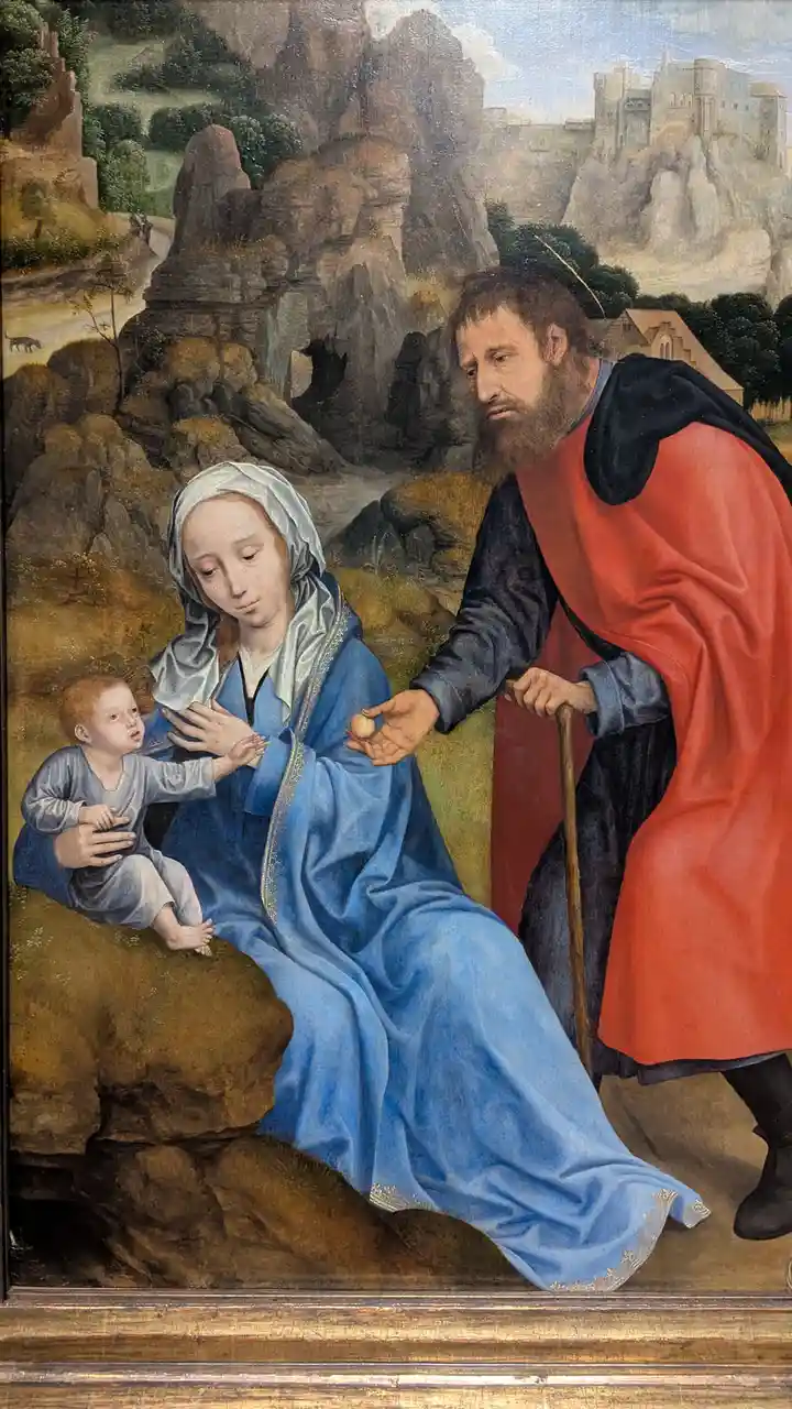 A classical religious painting depicts the Virgin Mary in a blue robe holding the infant Jesus, while Saint Joseph in a red…