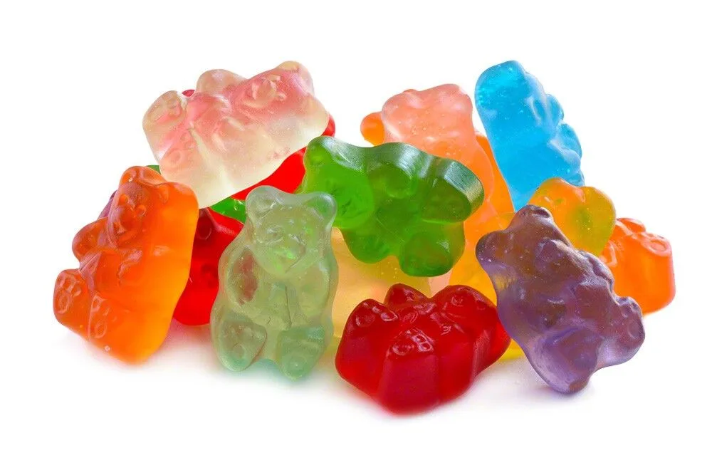 A pile of colorful, translucent gummy bears in various hues including red, orange, green, blue, and purple, arranged against…
