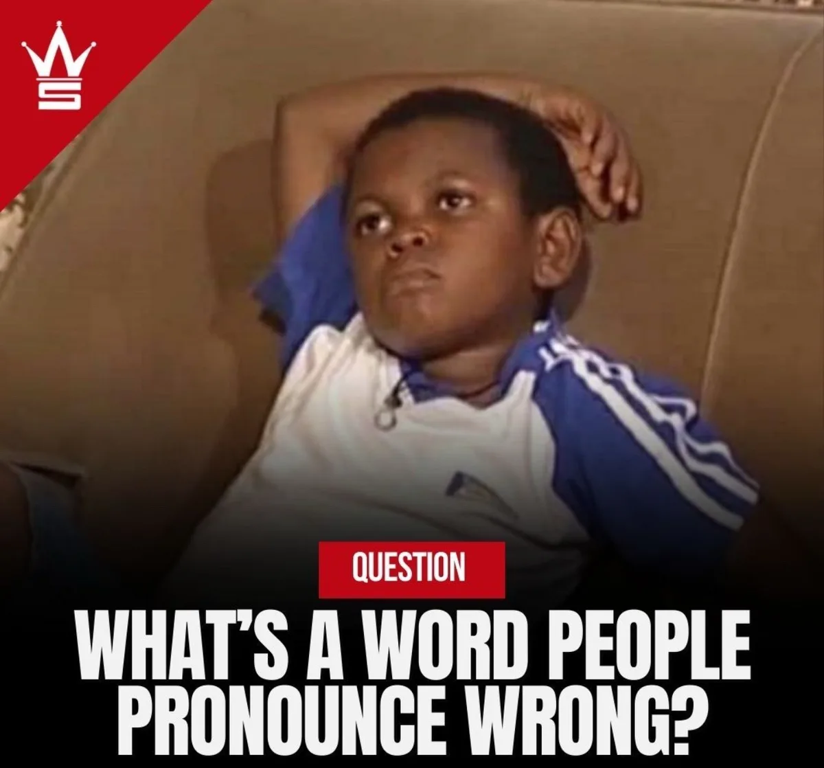 A young boy in a blue and white Adidas shirt lies on a brown couch with one arm behind his head, looking thoughtful…