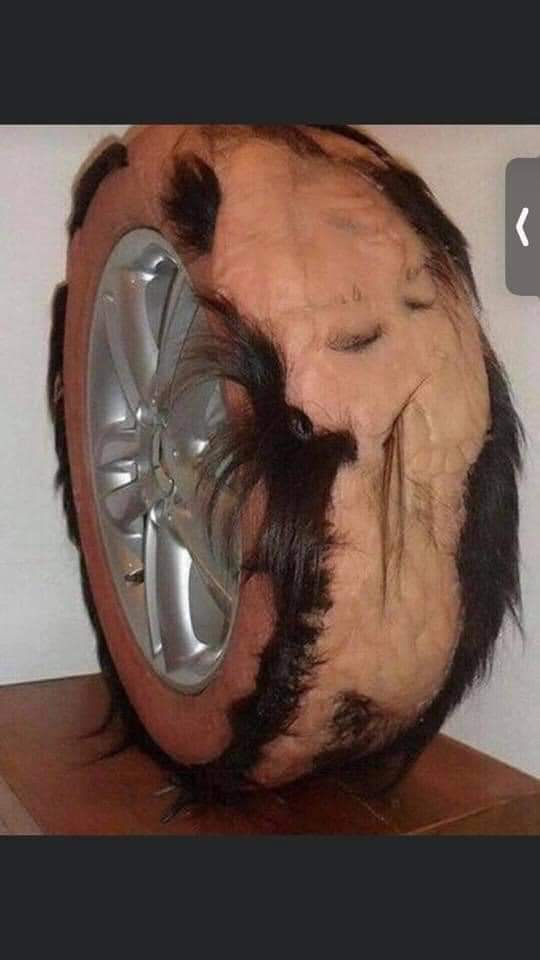 A person's head is visibly merged with a car tire, showing the tire's silver rim and rubber tread on one side, while the…