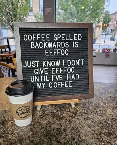 A letterboard sign in a coffee shop displays the text 'COFFEE SPELLED BACKWARDS IS EEFFOC JUST KNOW I DON'T GIVE EEFFOC…