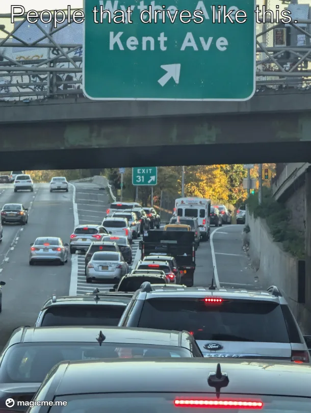 A photo of heavy traffic on a multi-lane highway with cars stopped or moving slowly, viewed from behind. A green overhead…